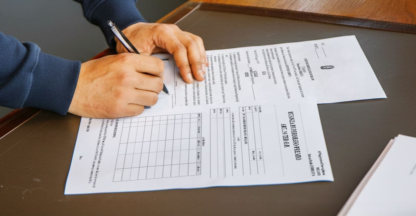 A hand filling in a form on a table.
